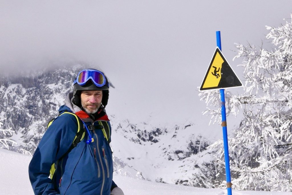 Bilden visar en skidåkare och en varningsskylt